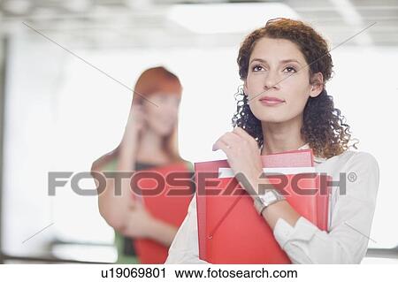 Businesswoman carrying folders in office View Large Photo Image Stock Image - Businesswoman carrying folders in office. Fotosearch