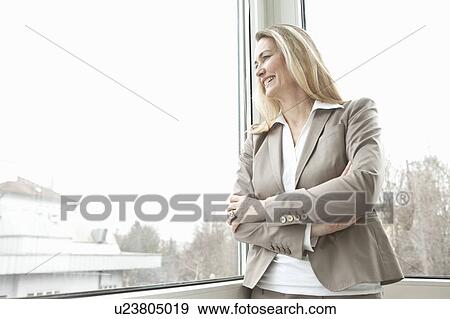 Businesswoman looking out window smiling View Large Photo Image Stock Photo - Businesswoman looking out window smiling. Fotosearch