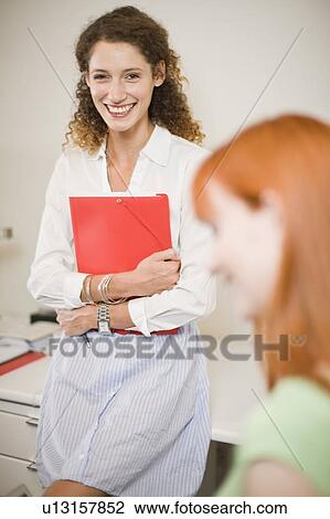 Businesswoman sitting on desk in office View Large Photo Image Stock Image - Businesswoman sitting on desk in office. Fotosearch