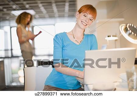 Stock Image - Businesswoman using laptop in office. Fotosearch