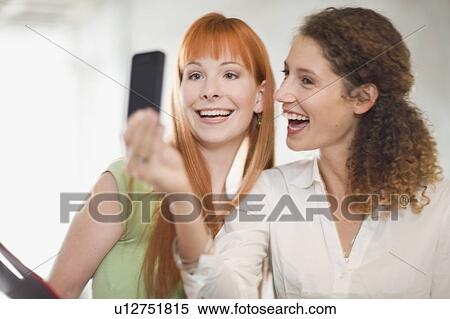 Stock Photography - Businesswomen using cell phone in office. Fotosearch