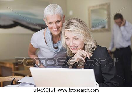 Businesswomen using laptop together View Large Photo Image Stock Image - Businesswomen using laptop together. Fotosearch