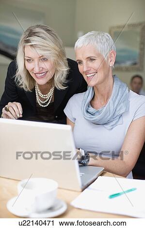 Businesswomen using laptop together View Large Photo Image Stock Image - Businesswomen using laptop together. Fotosearch