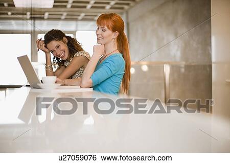 Stock Photograph - Businesswomen using laptop together. Fotosearch