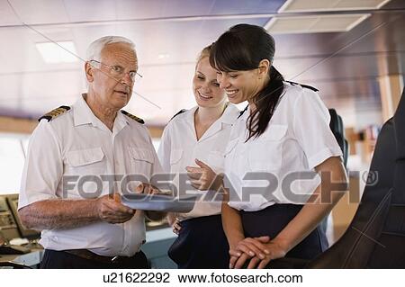 Stock Image - Captain giving advices to his assistants. Fotosearch