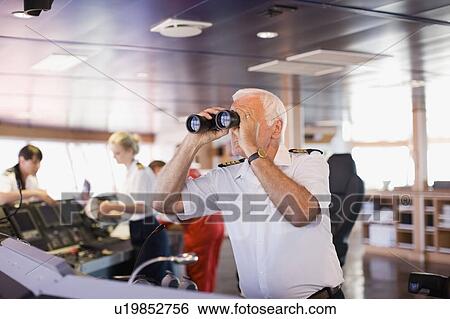 Stock Photograph - Captain on ship looking through a telescope. Fotosearch
