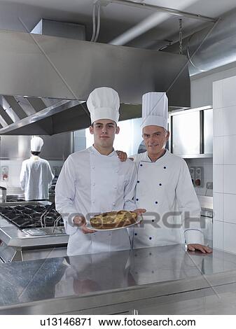 Stock Image - Chefs apprentice with home made cake. Fotosearch