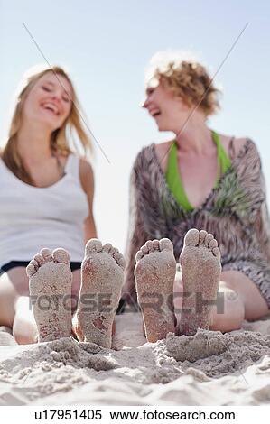 Stock Photography - Close up of women’s sandy feet on beach. Fotosearch