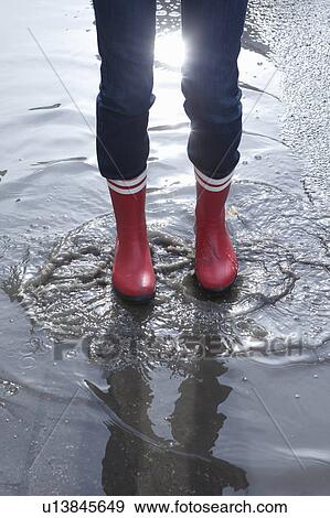 Stock Photo - Close up rubber boots in puddle. Fotosearch