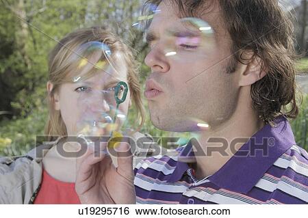 Couple blowing bubbles in park View Large Photo Image Stock Photograph - Couple blowing bubbles in park. Fotosearch