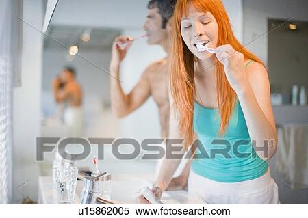 Stock Photography - Couple brushing their teeth in bathroom. Fotosearch