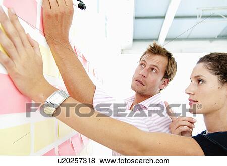 Stock Photo - Couple discuss data on board. Fotosearch