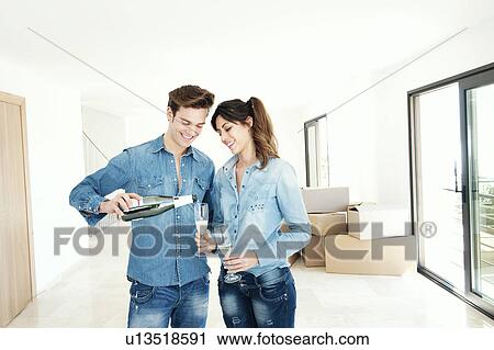 Stock Image - Couple drinking champagne in new home. Fotosearch