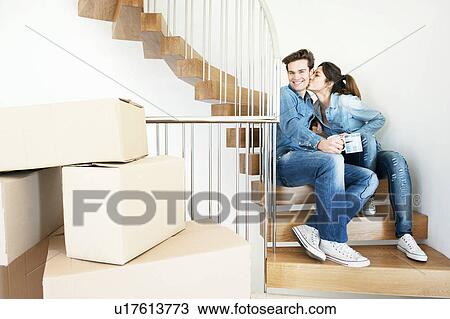 Stock Image - Couple drinking coffee in new home. Fotosearch
