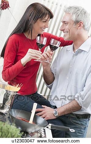 Couple drinking wine while cooking View Large Photo Image Stock Photo - Couple drinking wine while cooking. Fotosearch