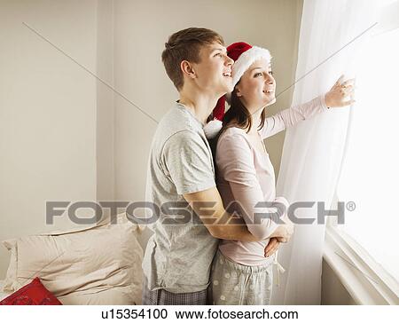 Stock Image - Couple embracing, looking out of window. Fotosearch
