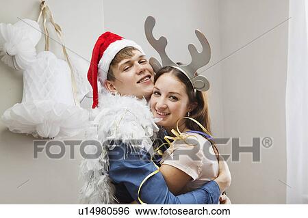 Couple embracing wearing christmas hats View Large Photo Image Stock Photograph - Couple embracing wearing christmas hats. Fotosearch