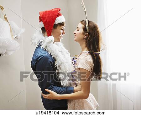 Picture - Couple embracing wearing christmashats. Fotosearch