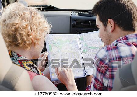 Stock Image - Couple examining map in jeep. Fotosearch