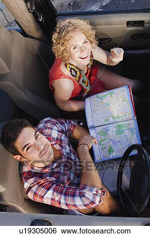 Stock Photograph - Couple examining map in jeep. Fotosearch