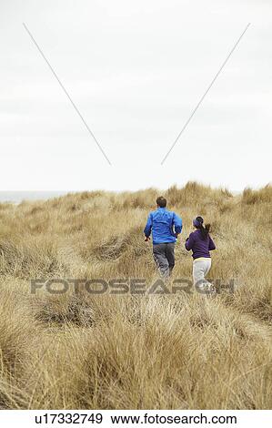 Couple exercising in long grass by sea View Large Photo Image Stock Photo - Couple exercising in long grass by sea. Fotosearch