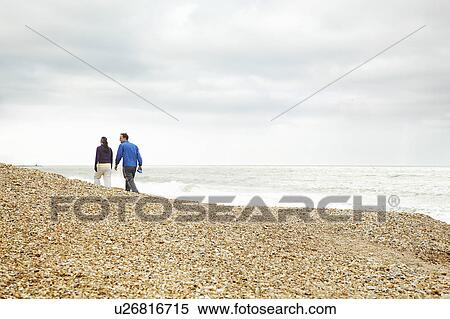 Stock Photography - Couple exercising on beach on cloudy day. Fotosearch