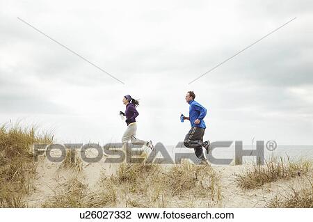 Couple exercising on sand dunes at beach View Large Photo Image Stock Image - Couple exercising on sand dunes at beach. Fotosearch