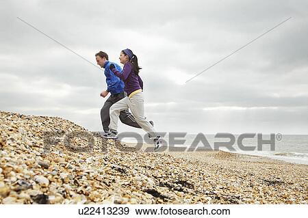 Couple exercising on stoney beach View Large Photo Image Stock Photo - Couple exercising on stoney beach. Fotosearch