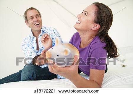 Stock Image - Couple fight over piggy bank. Fotosearch