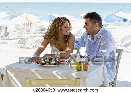 Stock Image - couple having lunch near the beach. Fotosearch