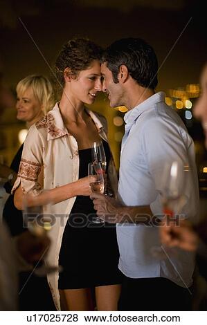 Stock Photo - Couple having wine on terrace at night. Fotosearch