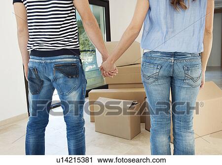 Stock Image - Couple holding hands in new home. Fotosearch