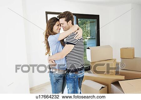 Stock Image - Couple hugging in new home. Fotosearch