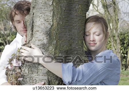 Couple hugging tree in park View Large Photo Image Stock Image - Couple hugging tree in park. Fotosearch