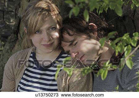 Couple hugging under a tree in park View Large Photo Image Stock Image - Couple hugging under a tree in park. Fotosearch