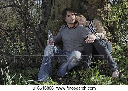 Couple hugging under a tree in park View Large Photo Image Stock Photograph - Couple hugging under a tree in park. Fotosearch
