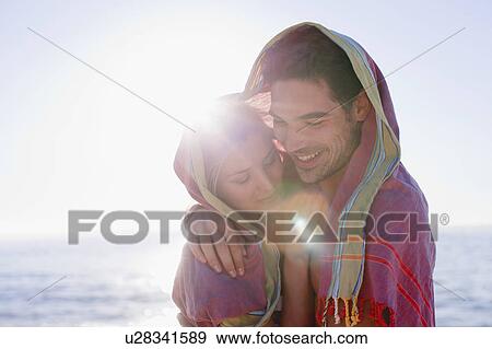 Couple hugging under blanket on beach View Large Photo Image Stock Photo - Couple hugging under blanket on beach. Fotosearch