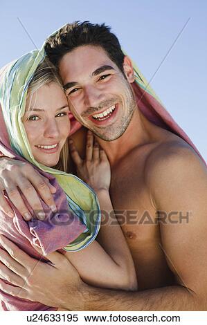 Stock Photography - Couple hugging under blanket on beach. Fotosearch