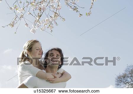 Stock Photo - Couple hugging under cherry blossom tree. Fotosearch
