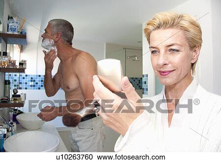 Stock Image - Couple in bathroom prepare for the day. Fotosearch