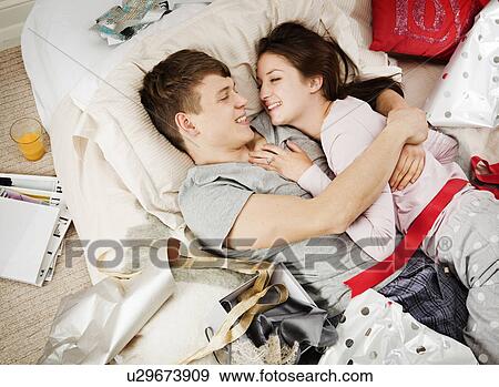 Stock Photo - Couple in bed laughing, with presents. Fotosearch