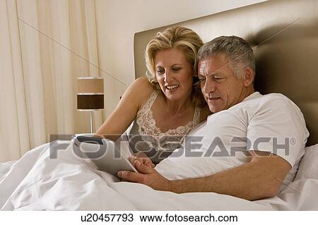 Couple in bed using tablet computer View Large Photo Image Stock Image - Couple in bed using tablet computer. Fotosearch