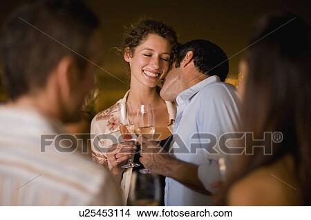Picture - Couple kissing at party at night. Fotosearch