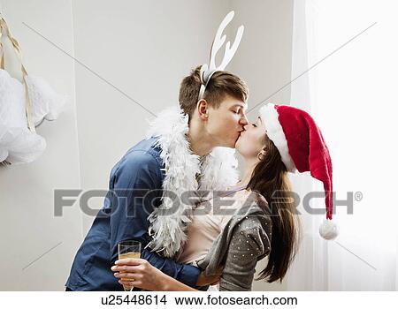 Couple kissing wearing christmashats View Large Photo Image Picture - Couple kissing wearing christmashats. Fotosearch