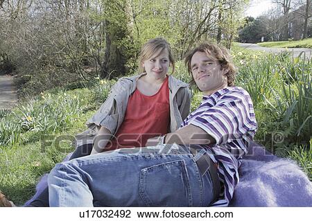 Stock Image - Couple laying on blanket in park. Fotosearch