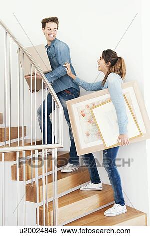 Couple moving boxes upstairs in new home View Large Photo Image Stock Photograph - Couple moving boxes upstairs in new home. Fotosearch