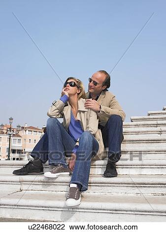 Stock Image - Couple on stairs by the marina. Fotosearch