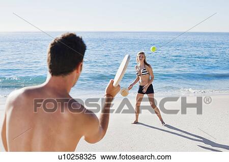 Stock Photography - Couple playing tennis on beach. Fotosearch