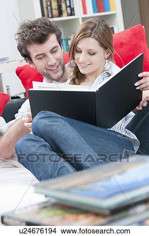 Couple reading together a book on sofa View Large Photo Image Picture - Couple reading together a book on sofa. Fotosearch