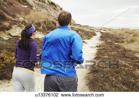 Stock Image - Couple running along coastal path. Fotosearch